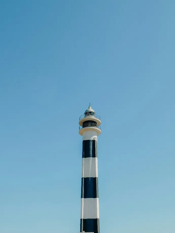 A black and white striped lighthouse on a beach