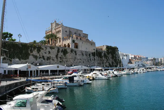 white and black boats on sea near brown concrete building during daytime